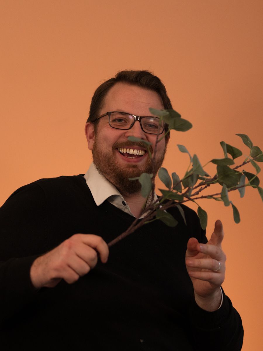 Uformelt bilde av Adrian der han vifter med en kvist og smiler