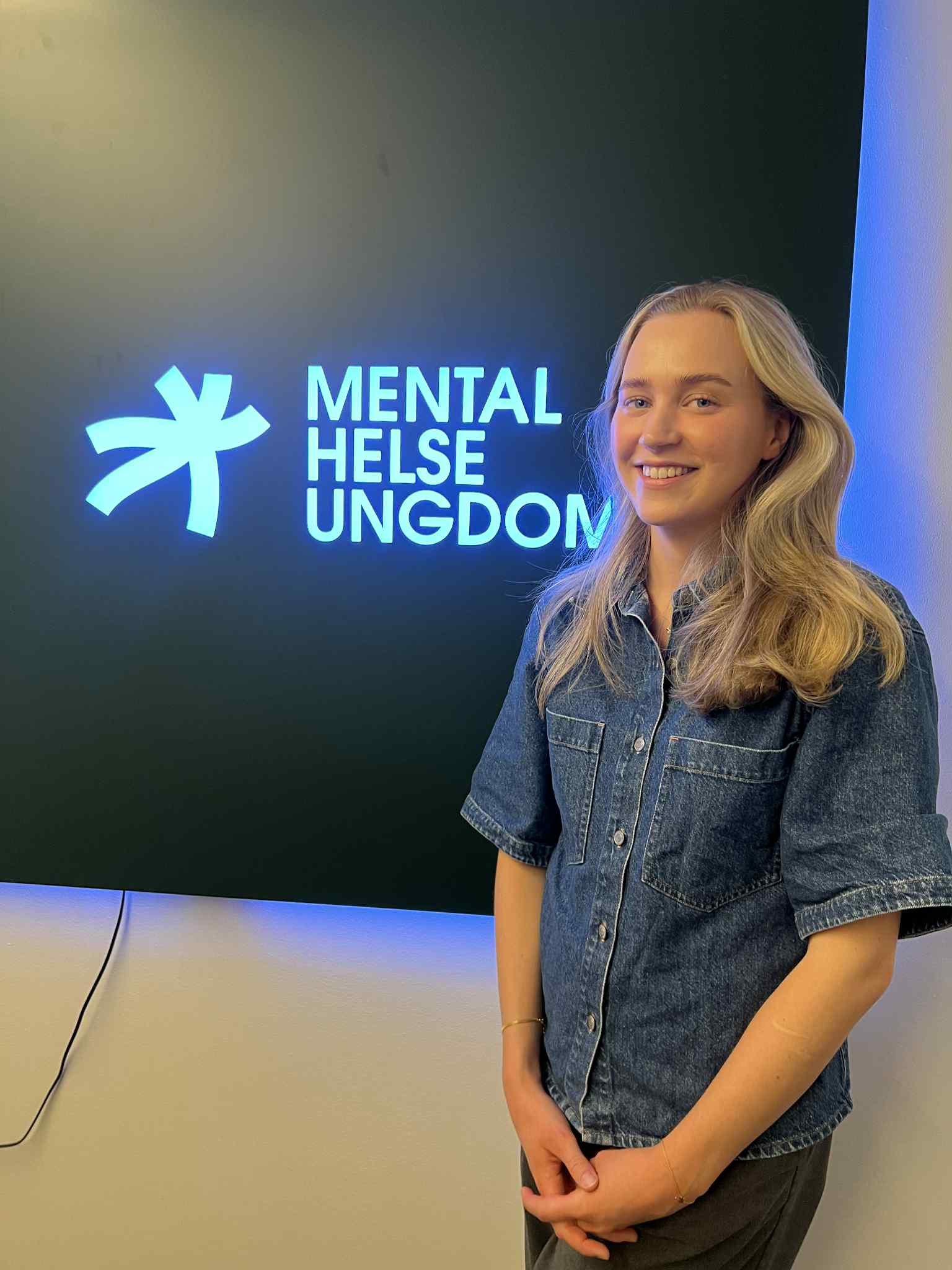 Bilde av Nikoline foran Mental Helse Ungdom-skilt