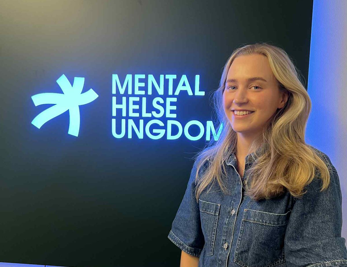 Bilde av Nikoline, foran skiltet med Mental Helse Ungdom