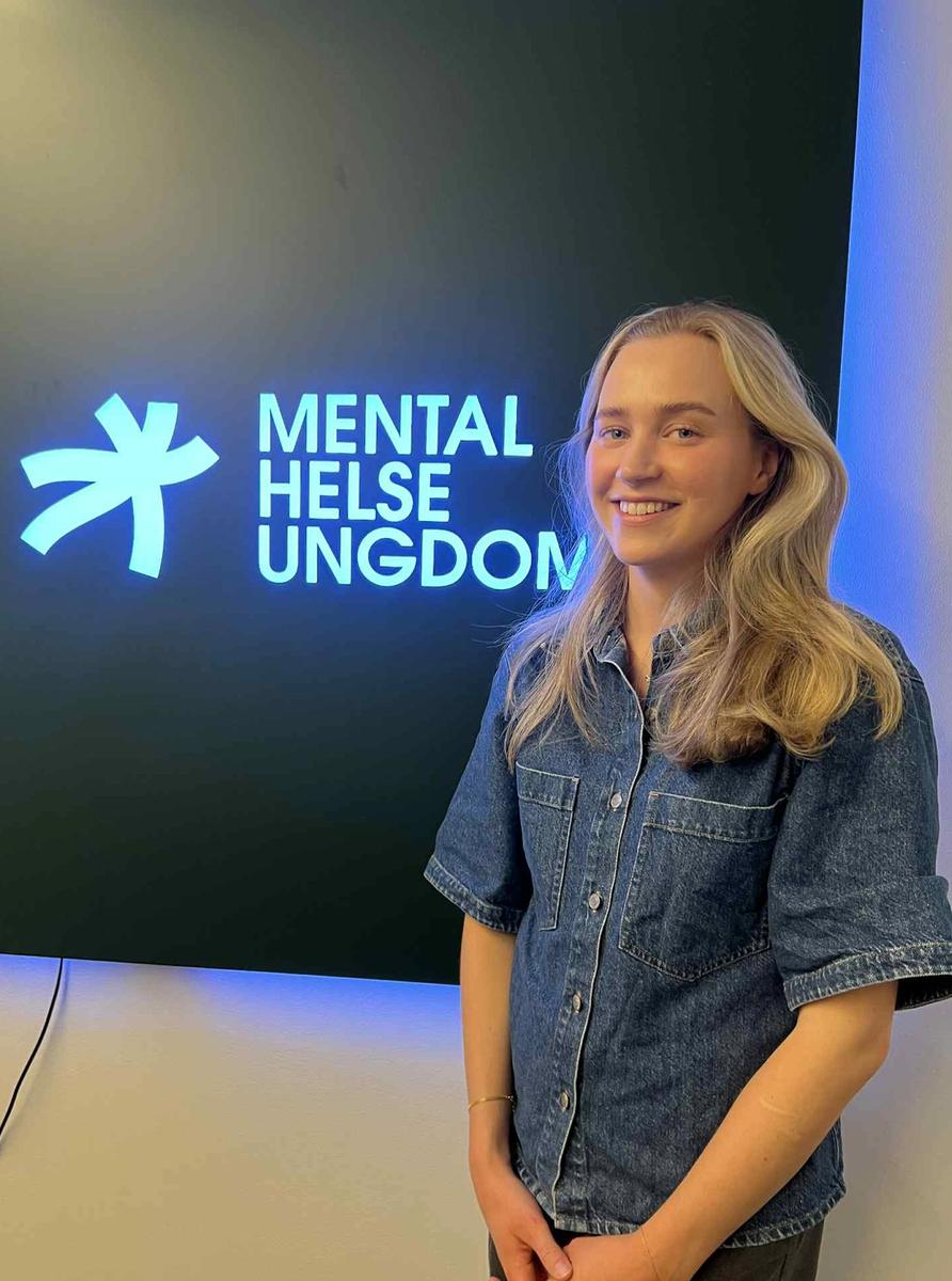 Bilde av Nikoline foran Mental Helse Ungdom-skilt