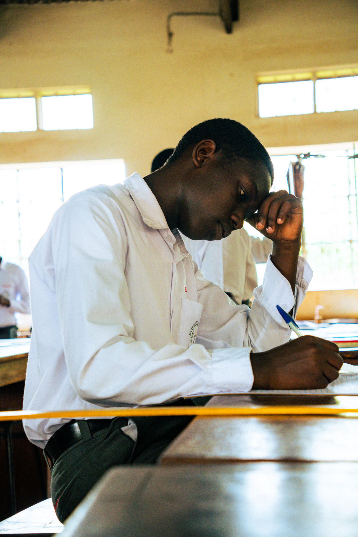 Mann ved skolepult som ettertenksomt hviler hodet på hånden