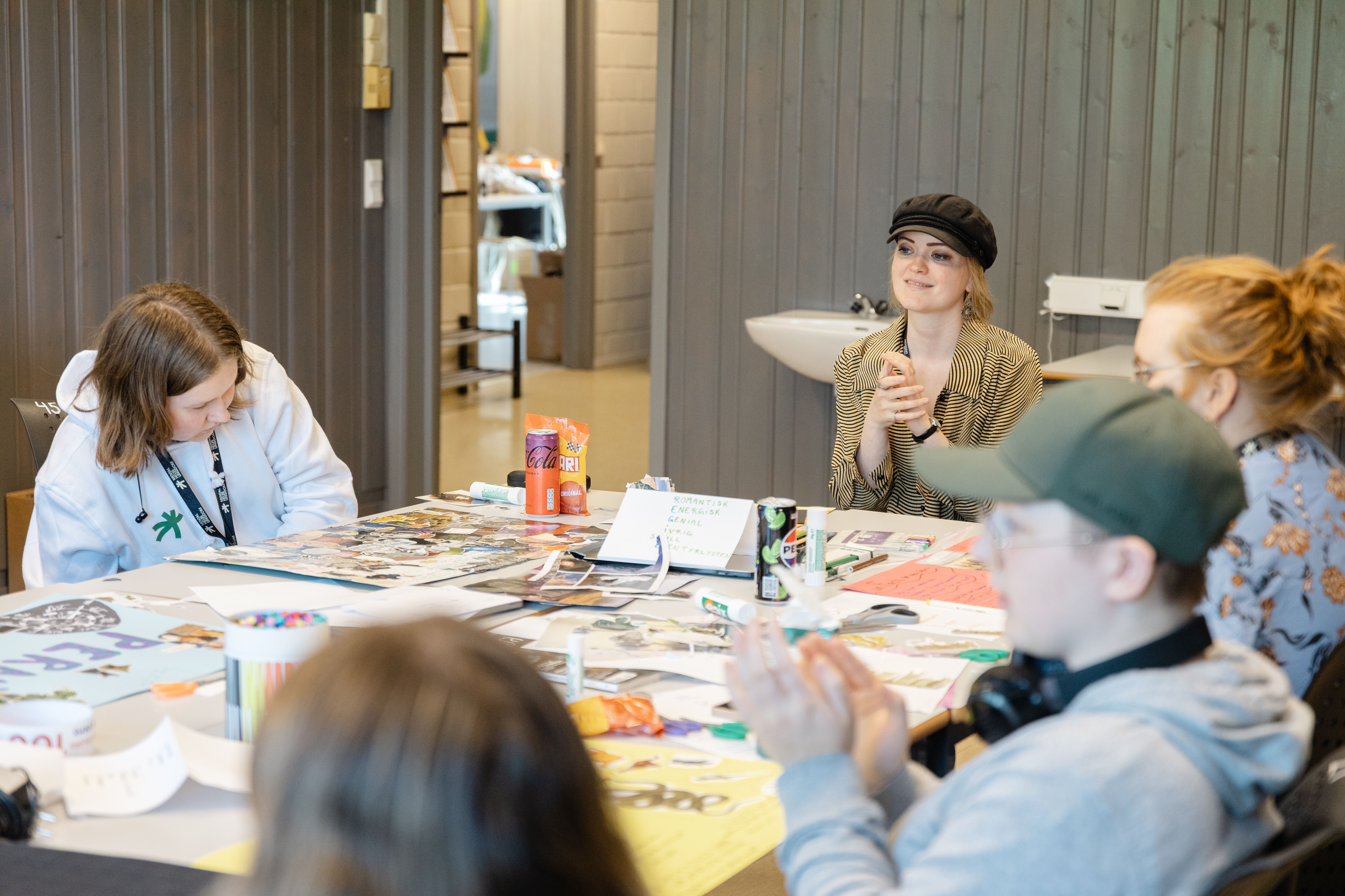 Folk rundt et bord fylt av magasiner og utklipp