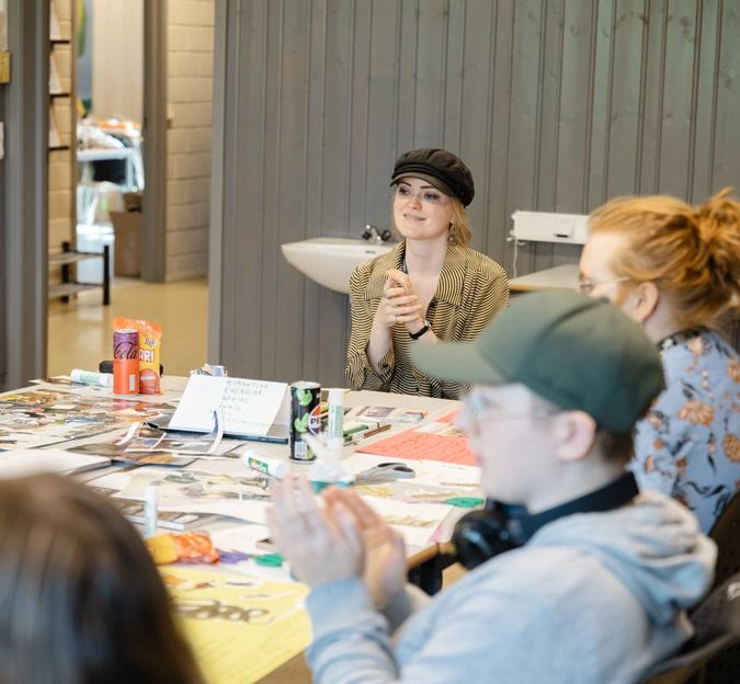 Folk rundt et bord fylt av magasiner og utklipp