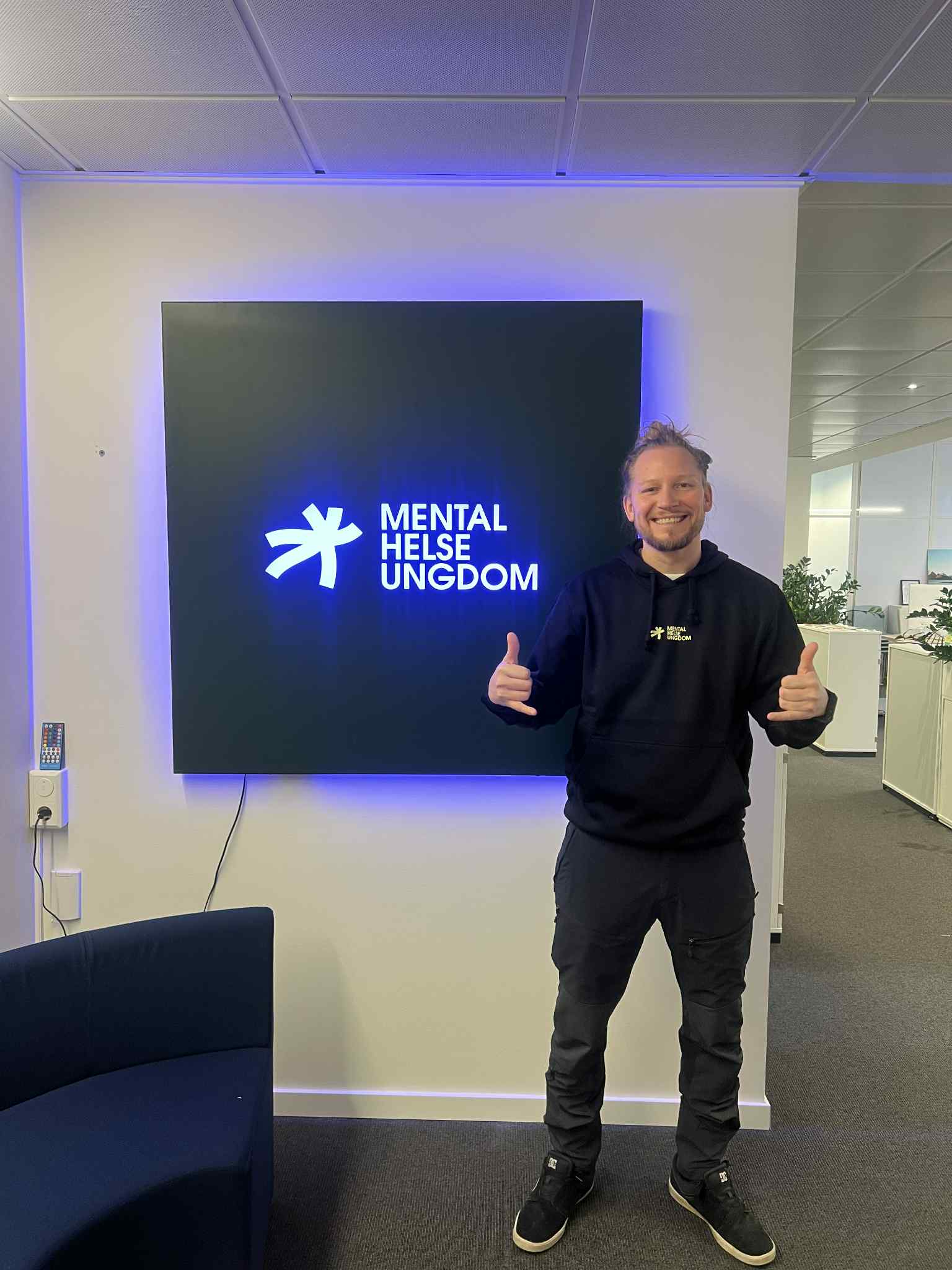 Bilde av Fredrik Huth Jensen foran Mental Helse Ungdom-skilt
