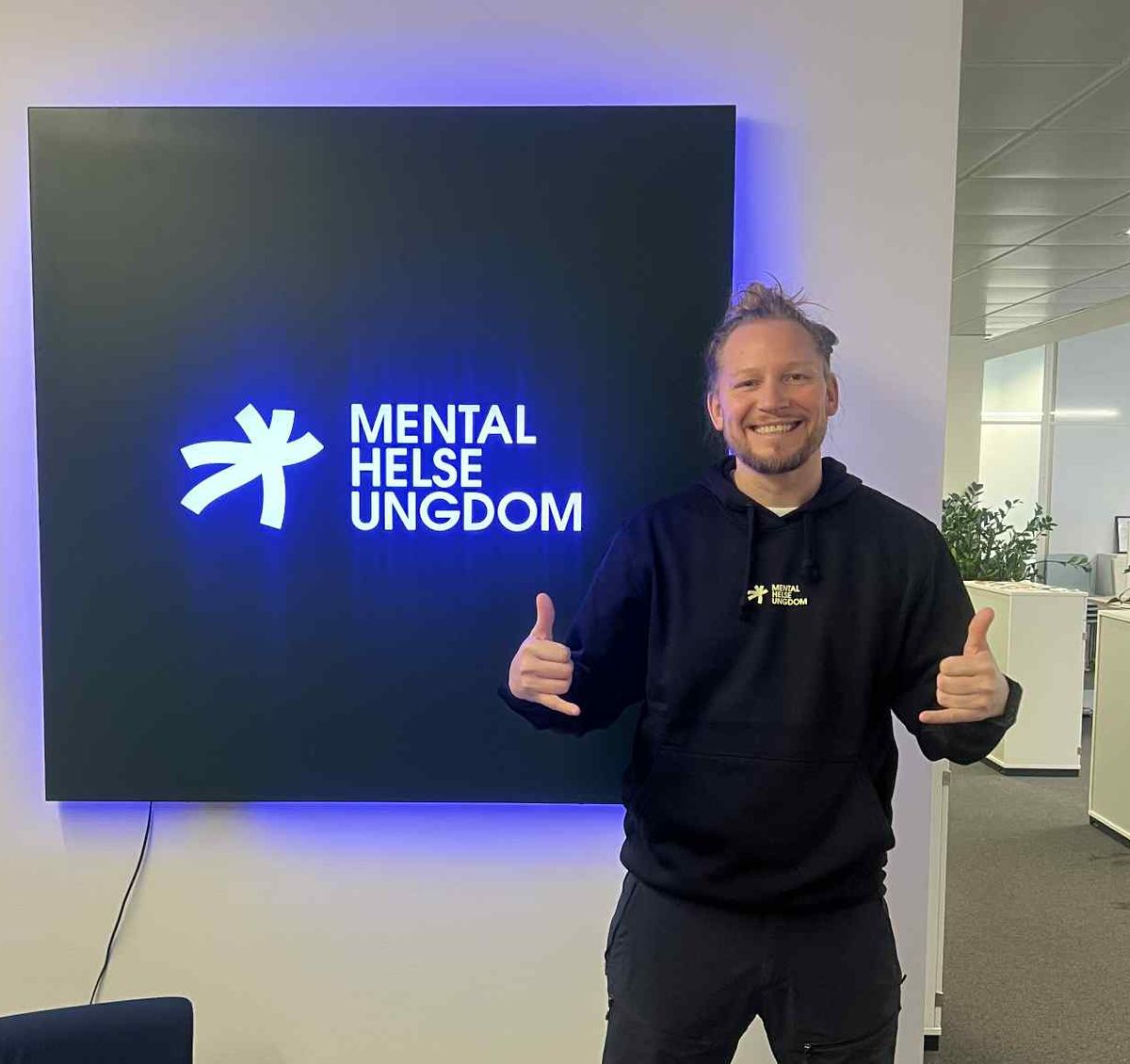 Bilde av Fredrik Huth Jensen foran Mental Helse Ungdom-skilt