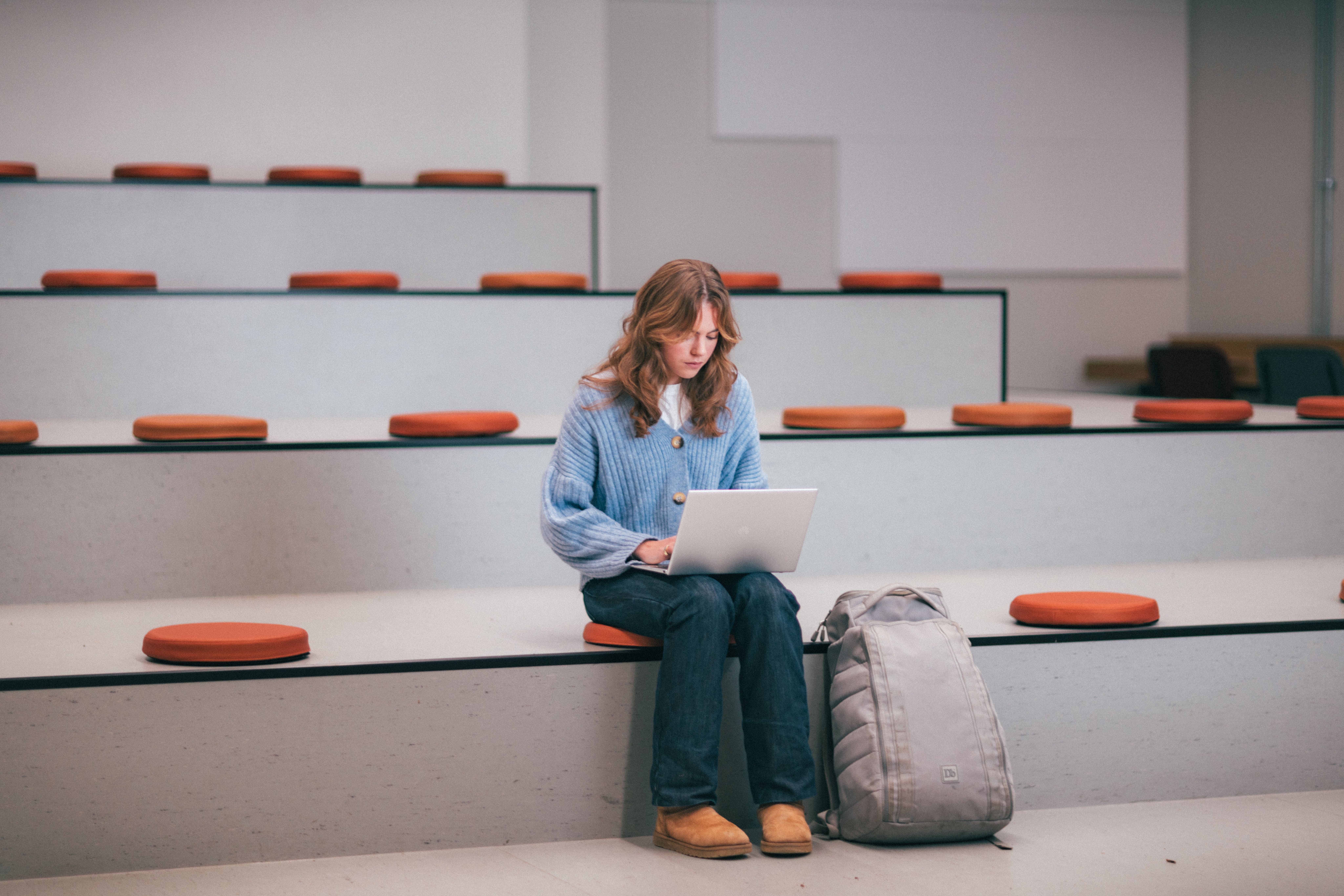 Ung jente i auditorium med laptop på fanget