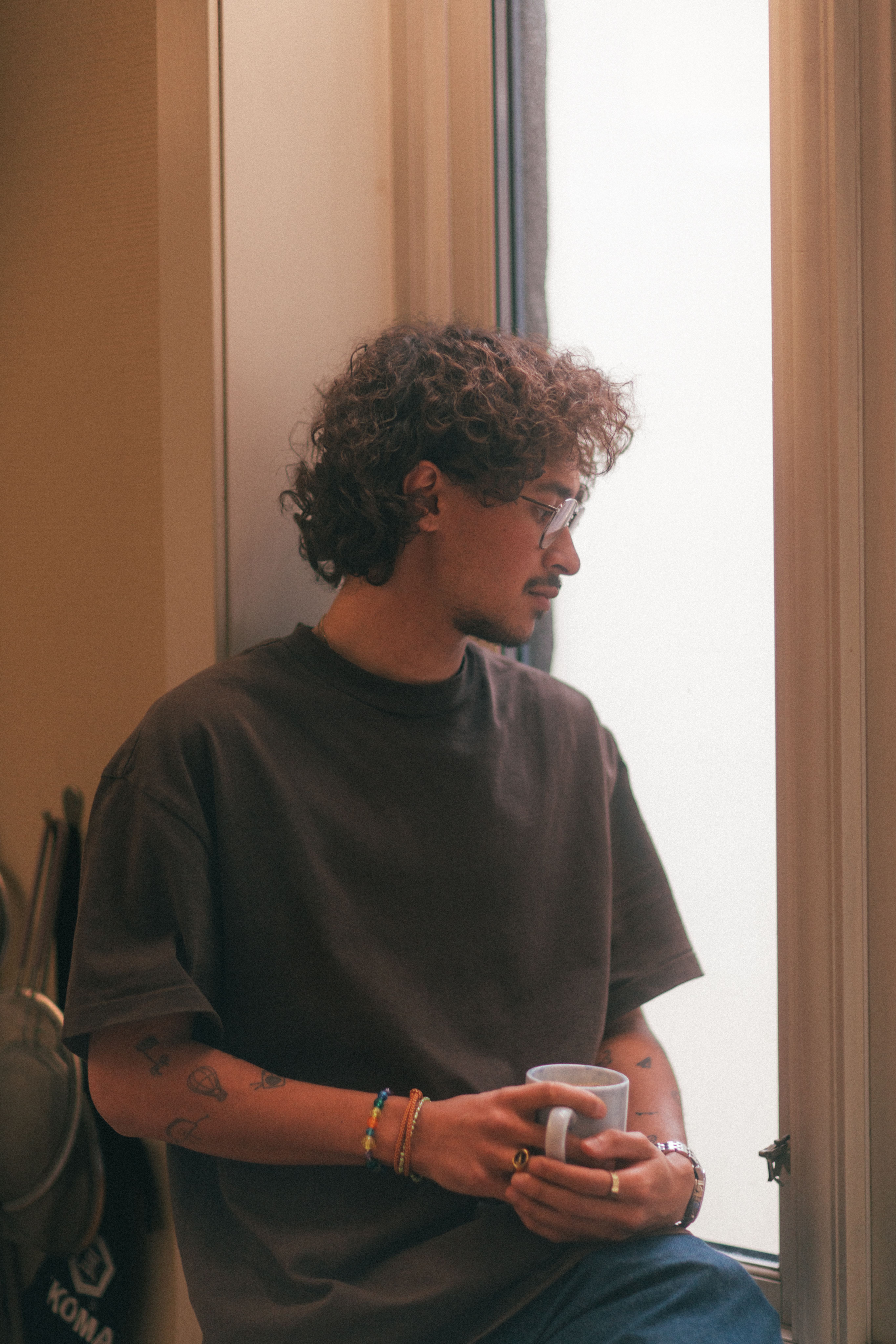 Mann ser ut av vinduet mens han holder en kopp