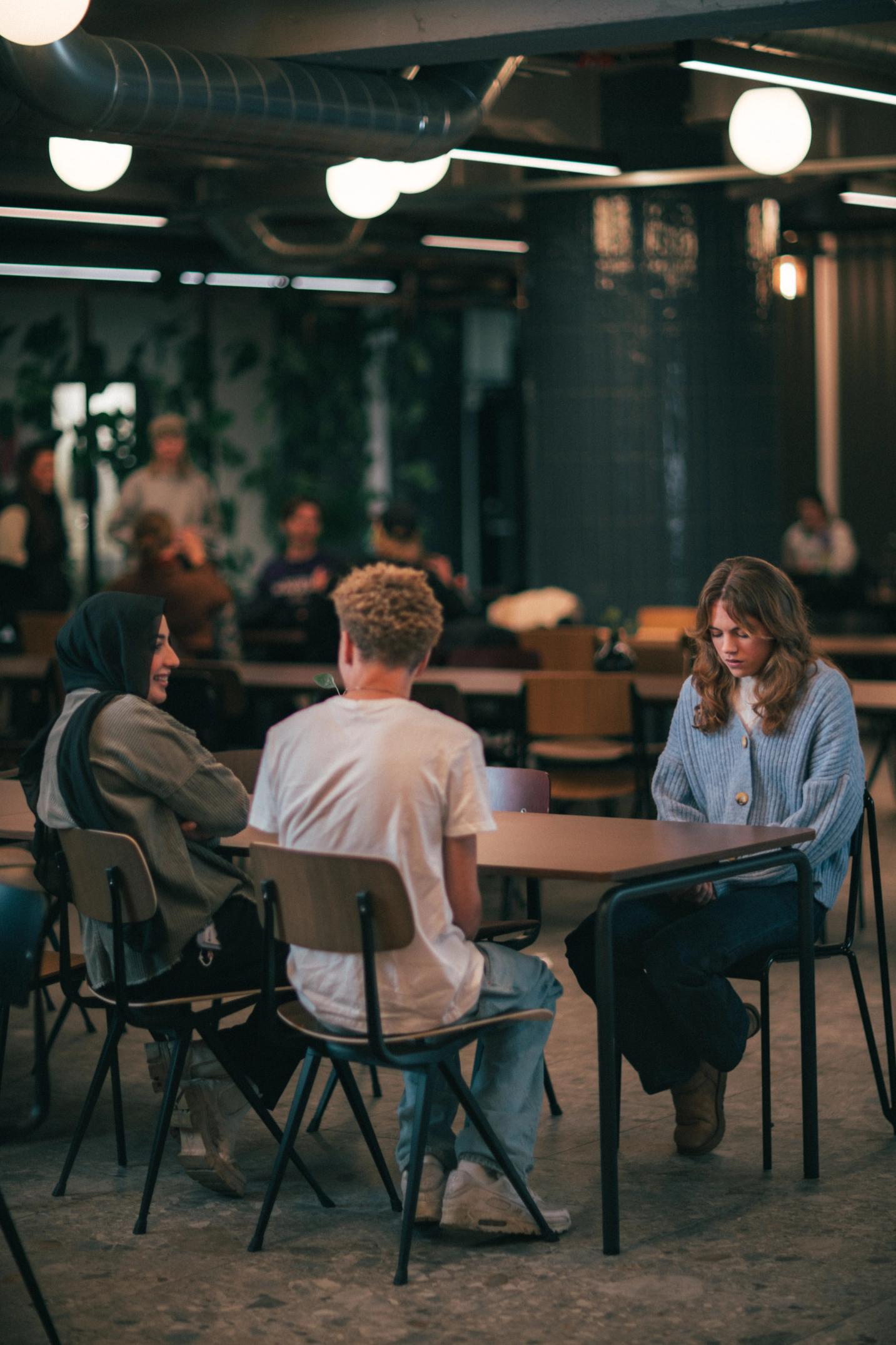 3 venner som sitter rundt et bord i skolekantinen
