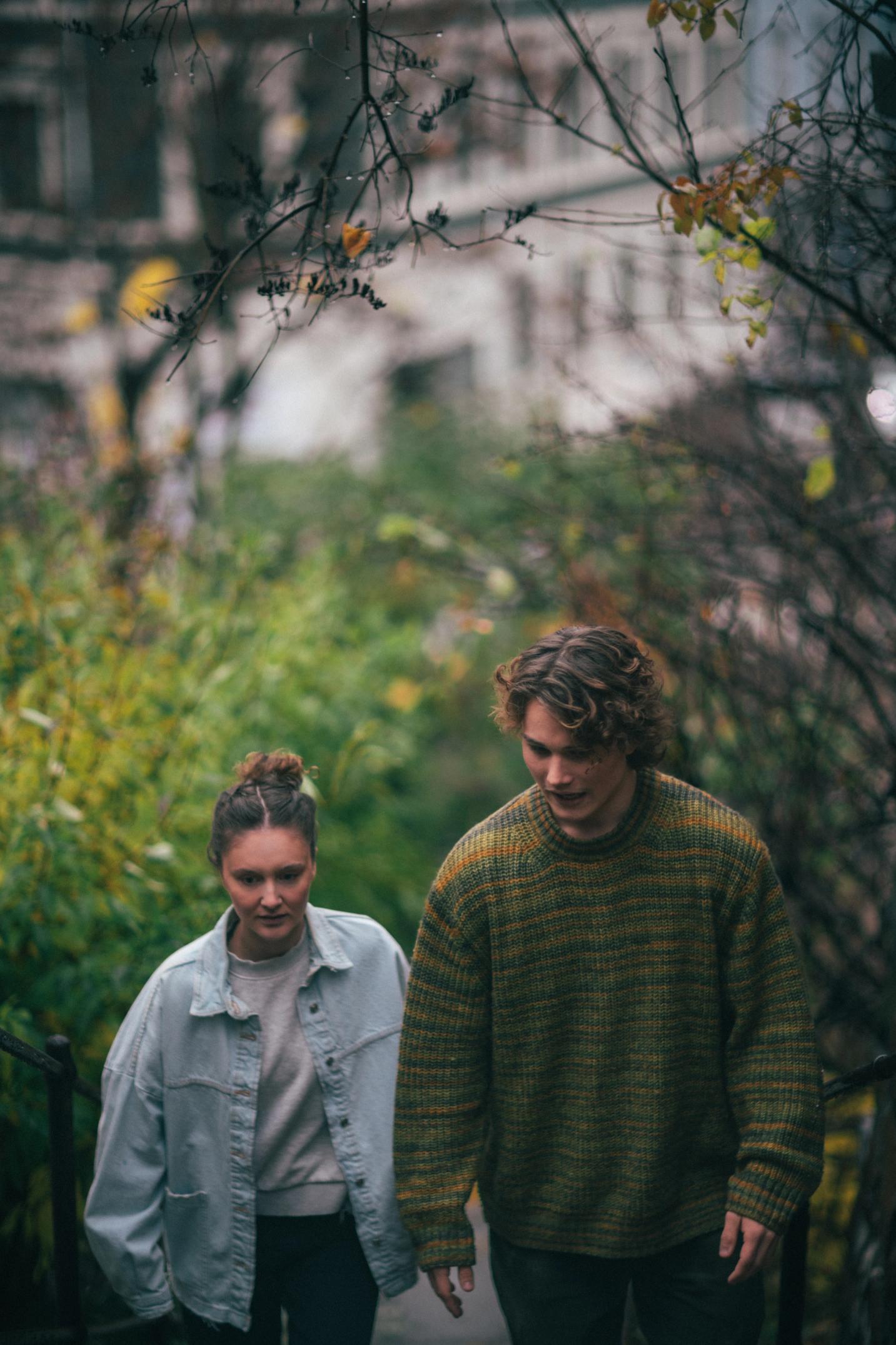To personer som går opp en trapp med natur rundt seg