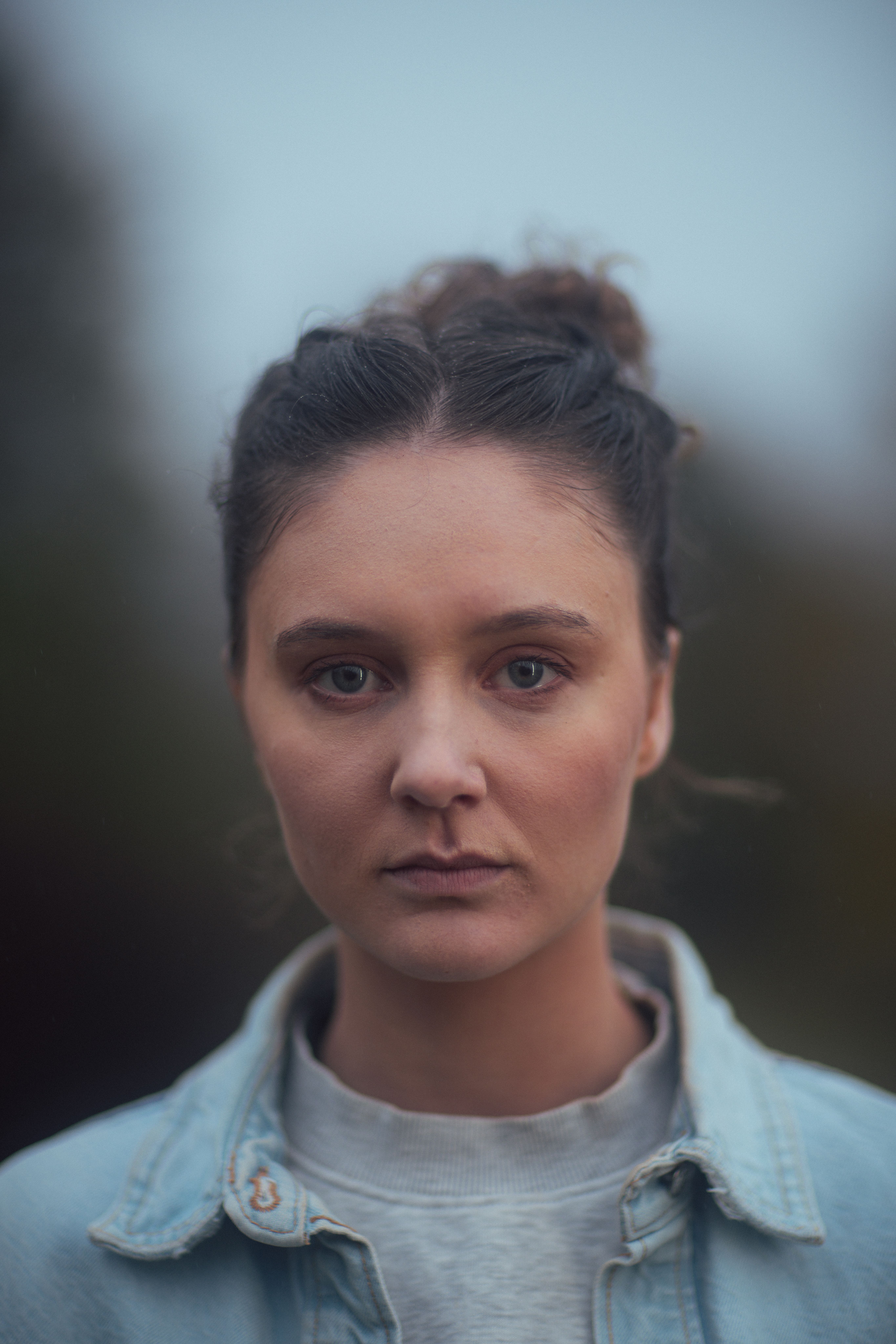 Jente som står utendørs og ser rett inn i kamera. Portrett.