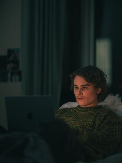 Gutt ser på laptop i mørket i sengen