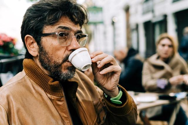 A man sips espresso at an outdoor table in Rome, Italy