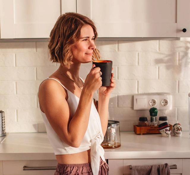 Woman enjoying homemade coffee in her kitchen