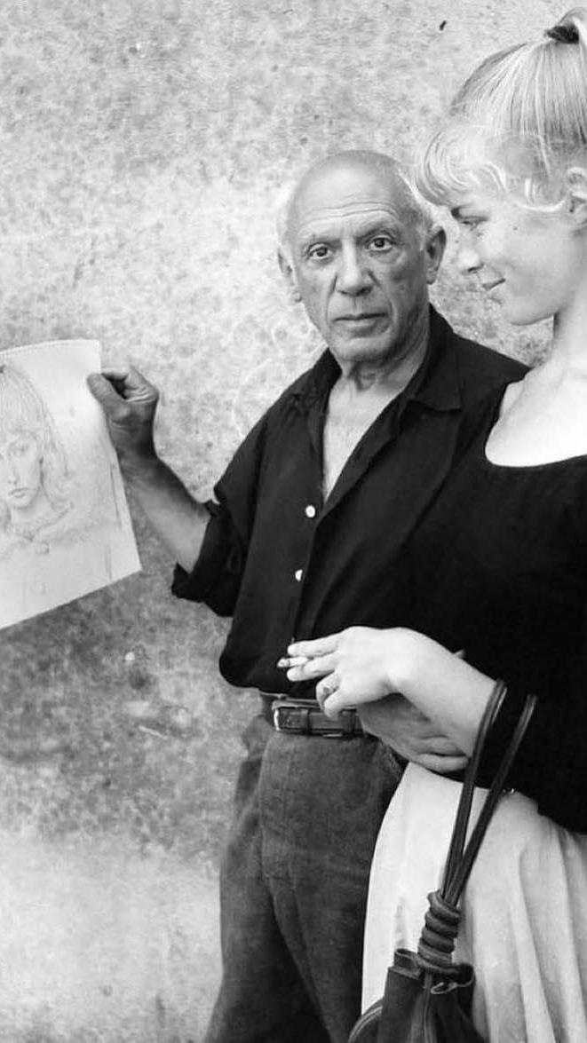 a man is holding a drawing of a woman while a woman looks on
