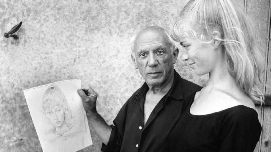 a man is holding a drawing of a woman while a woman looks on