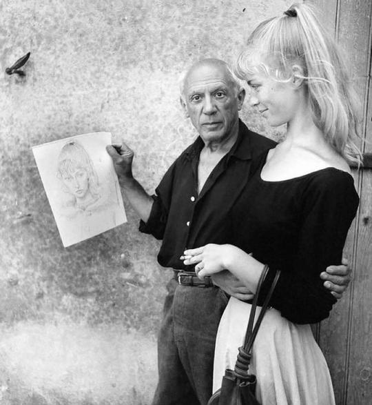 a man is holding a drawing of a woman while a woman looks on