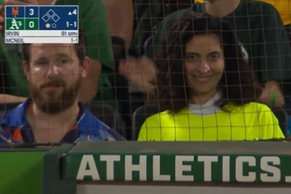 a man and a woman are sitting in a stadium behind a athletics sign