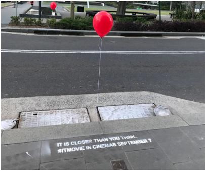 a red balloon is tied to a manhole cover on the side of the road .