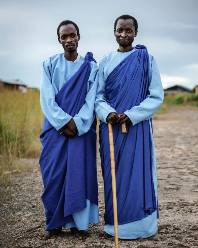 two men in blue robes stand next to each other