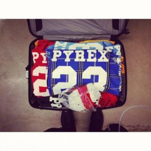 a person is standing next to a suitcase filled with pyrex clothes