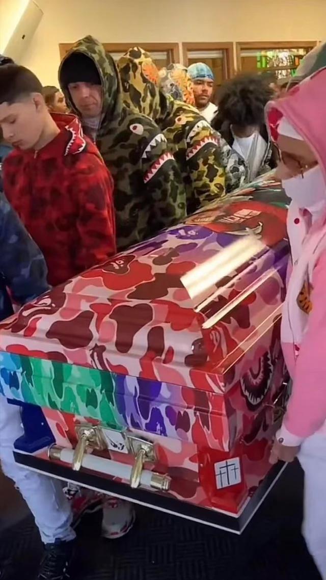 a group of people are carrying a coffin with a camouflage pattern on it .