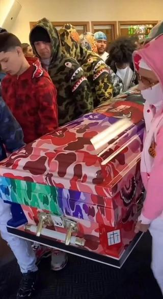 a group of people are carrying a coffin with a camouflage pattern on it .