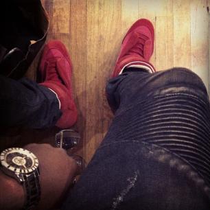 a person wearing a watch and a pair of red shoes