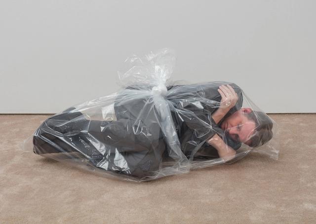 a man is laying on the floor wrapped in a plastic bag .