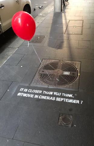 a red balloon is tied to a manhole cover with a sign that says it is closer than you think
