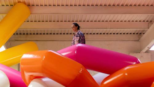 a woman is standing in a room filled with colorful inflatable balloons .