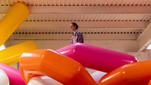 a woman is standing in a room filled with colorful inflatable balloons .