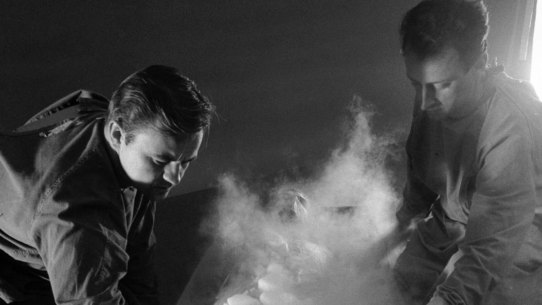two men are kneeling over a box filled with ice