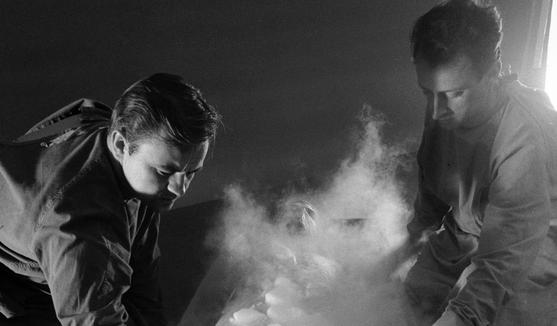 two men are kneeling over a box filled with ice