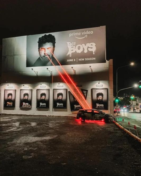 a car is parked in front of a billboard for the boys