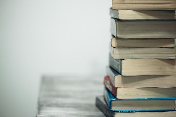 Image is of a stack of books. Text covers the different type of supplemental essays seen in college applications and the purpose of each. 