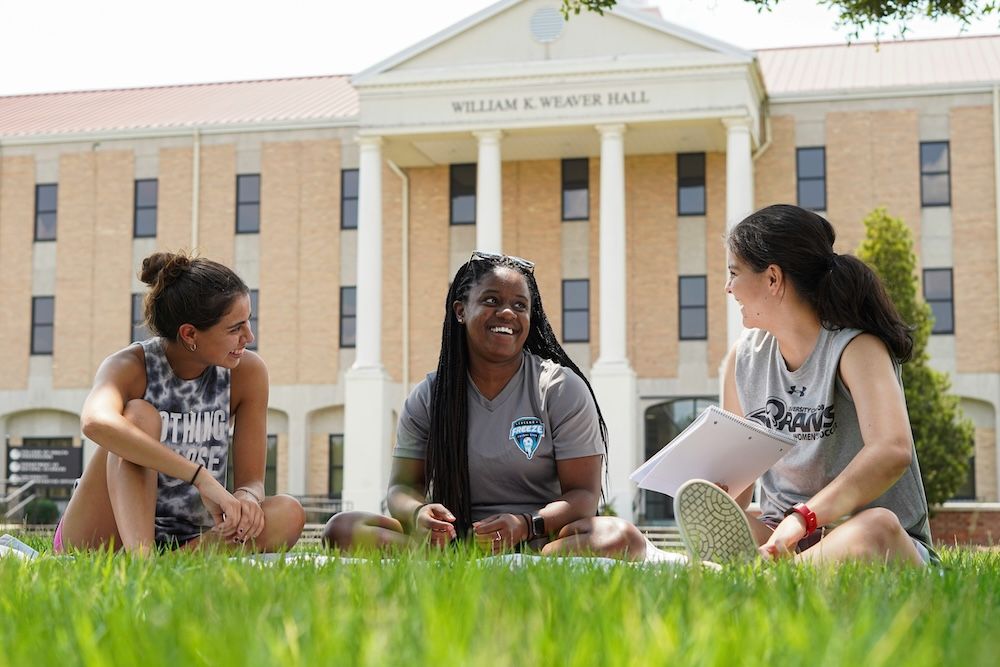 Students studying outside a college on a lawn