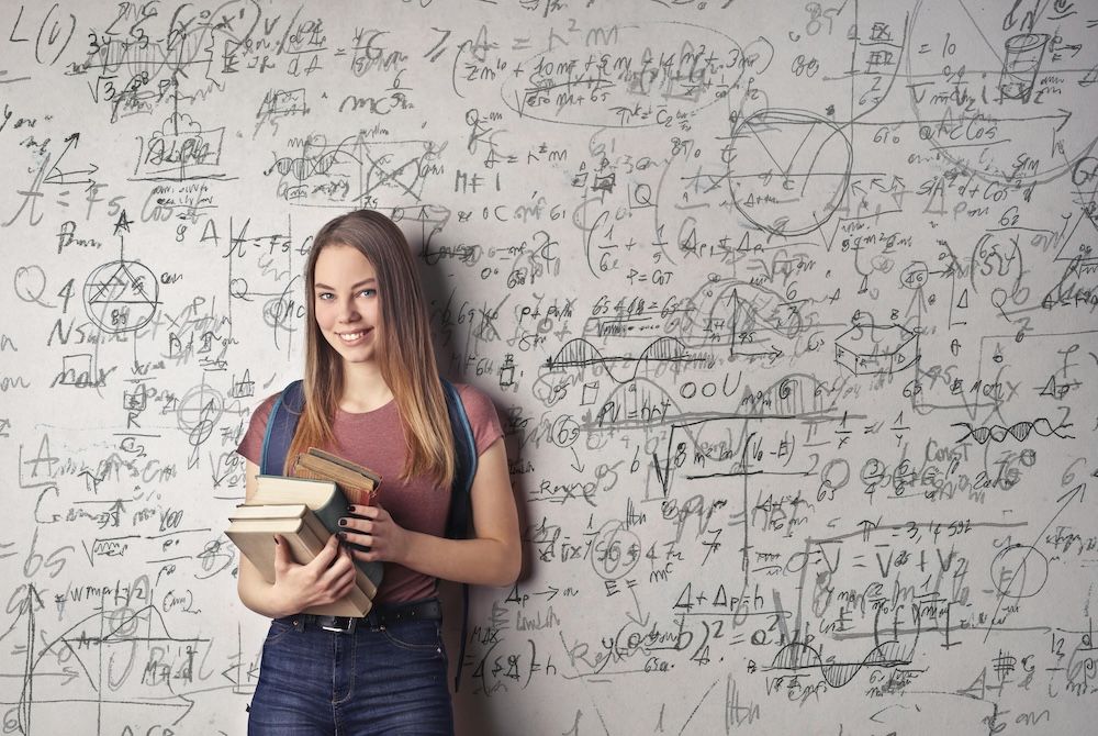 Student standing in front of a white board with math equations
