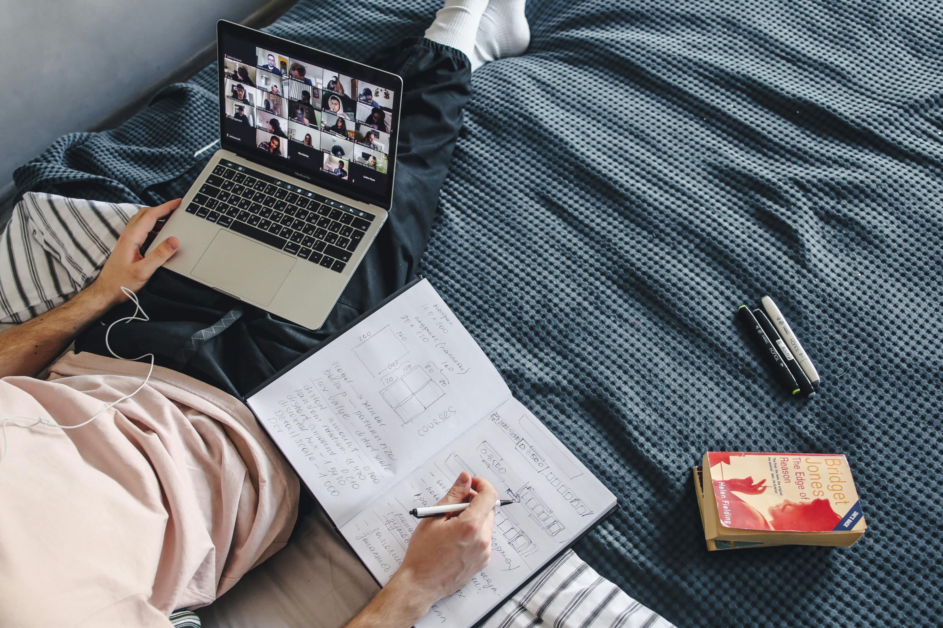 Student studying on bed in a virtual class. 