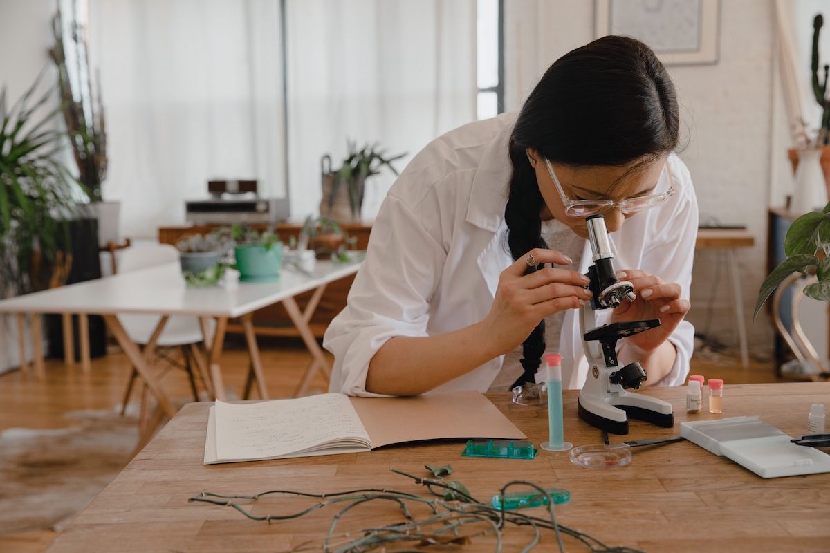 Student at a desk doing research looking through a microscope. Student at a desk doing research looking through a microscope.