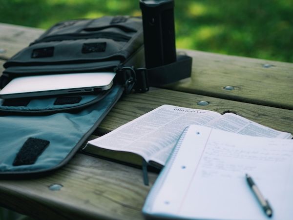 Image is of a backpack, book and notebook. Text addresses the difference between personal and supplemental college essays. 