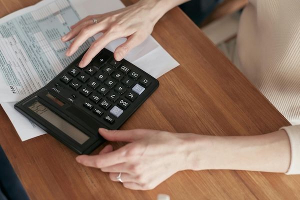 Image shows woman's hand and calculator. Text answers how middle class families can afford private school. 