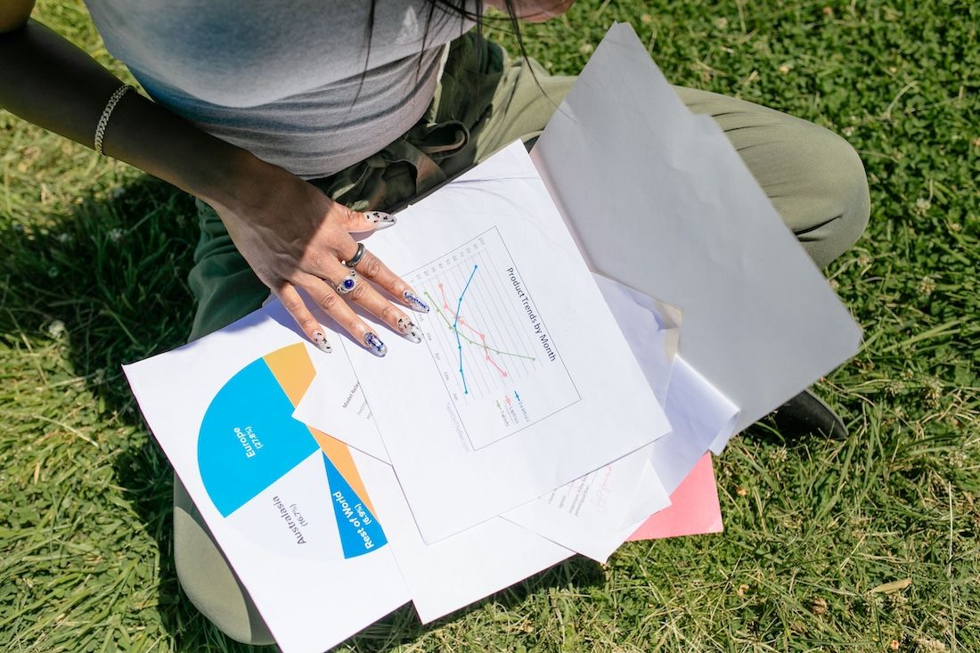 Student sitting on grass looking through research charts Student sitting on grass looking through research charts