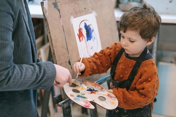 Young boy pants using easel and artist's palette. Example of an enrichment activity for gifted children. 