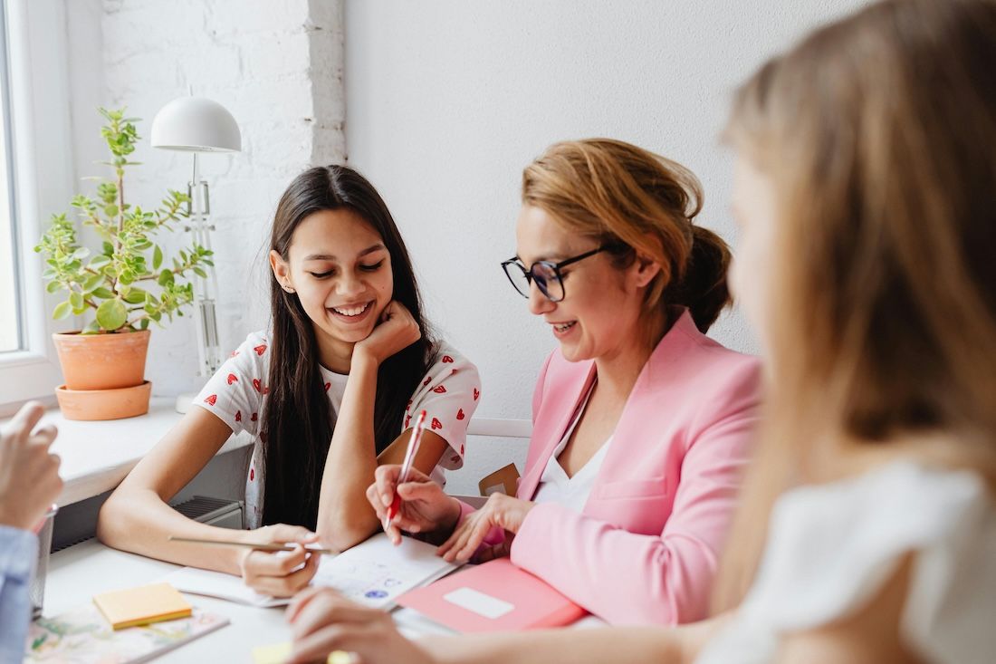 Students and teacher meeting at a table Students and teacher meeting at a table
