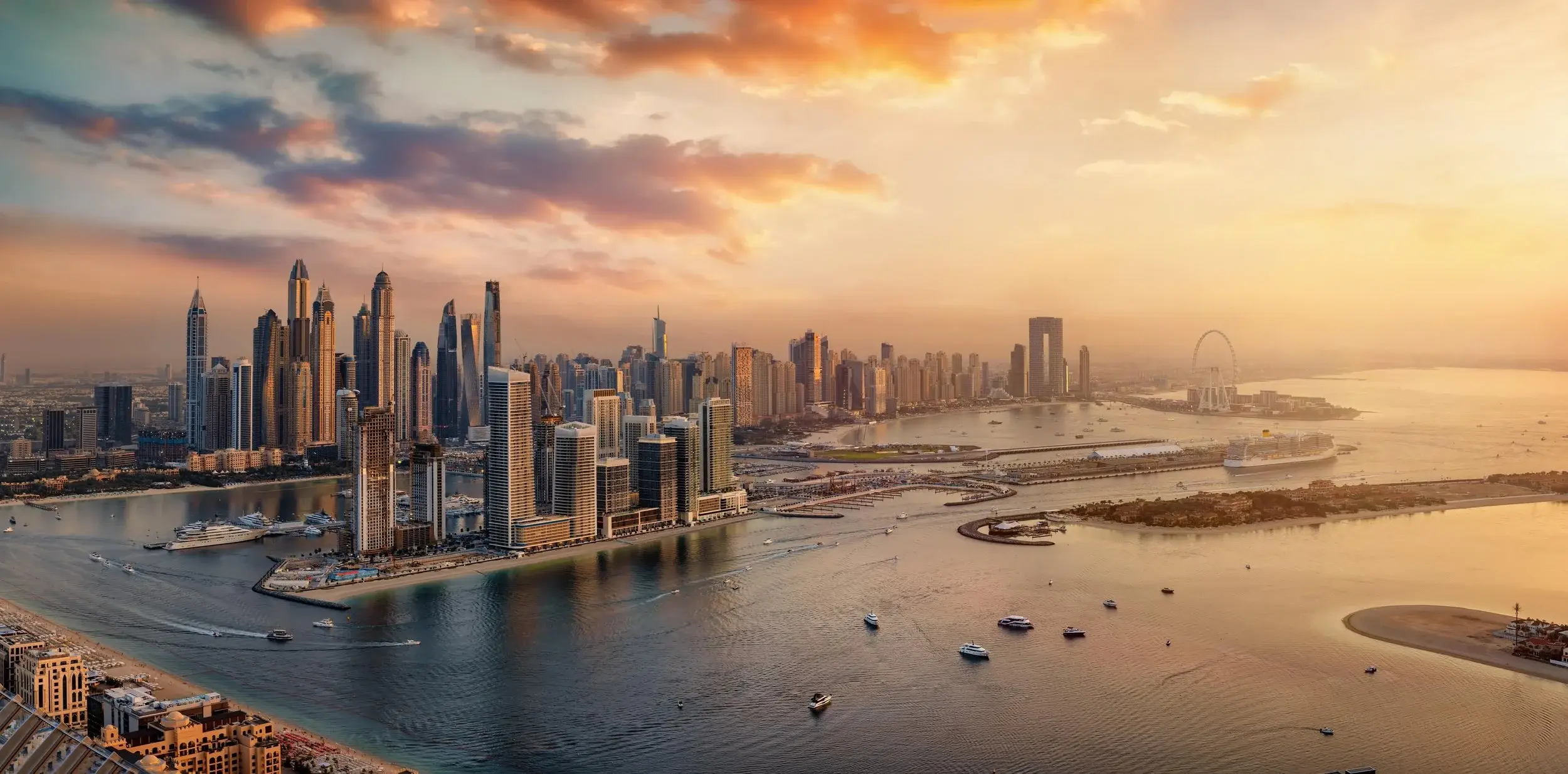 Yachts cruising near Dubai Marina with the city skyline at sunset