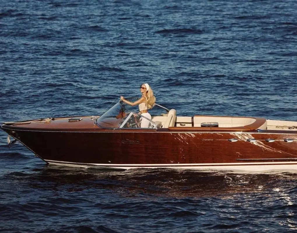 Woman cruising on a classic wooden yacht across deep blue Mediterranean water