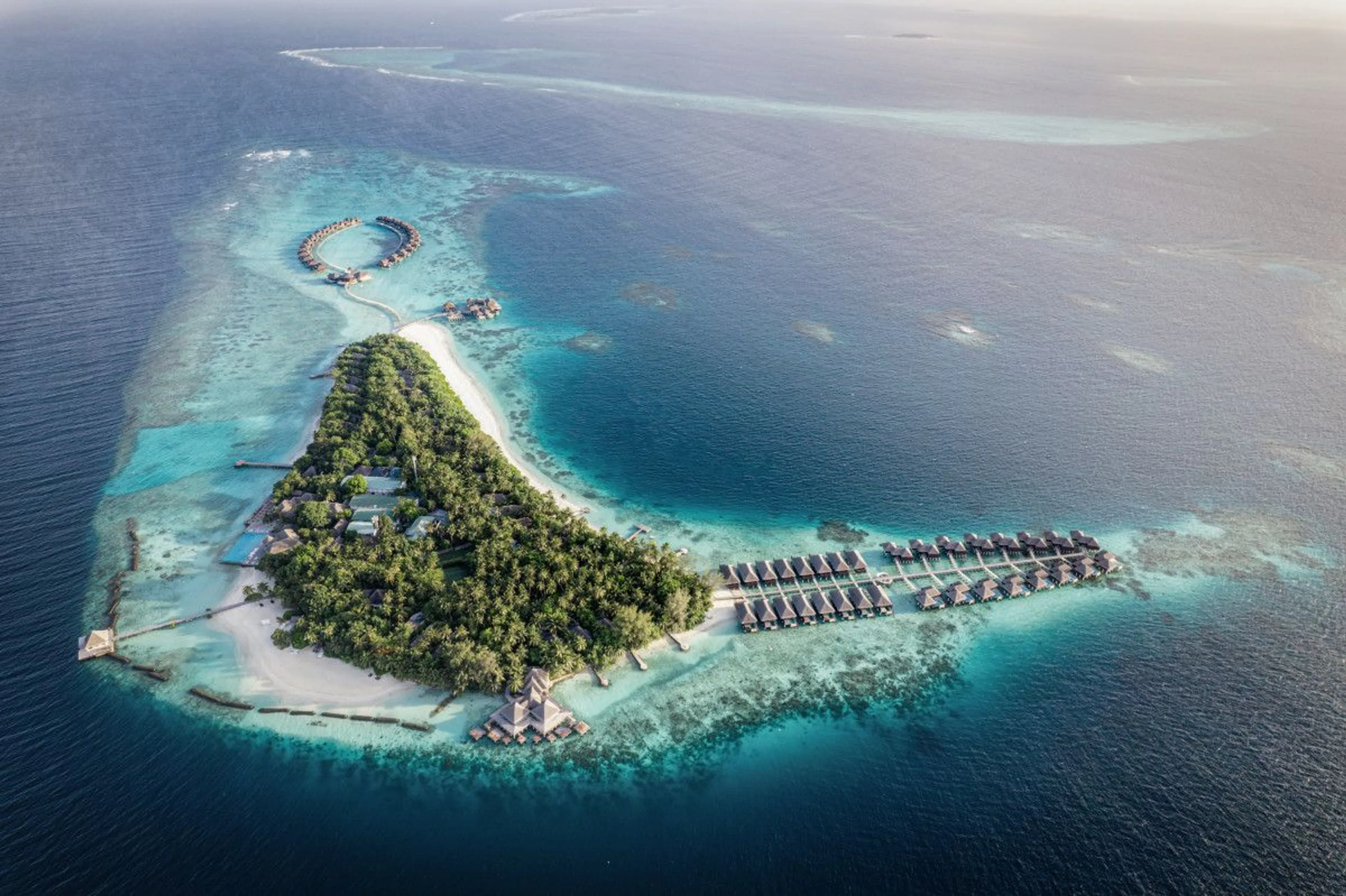 Private Maldives island surrounded by turquoise lagoons and overwater villas