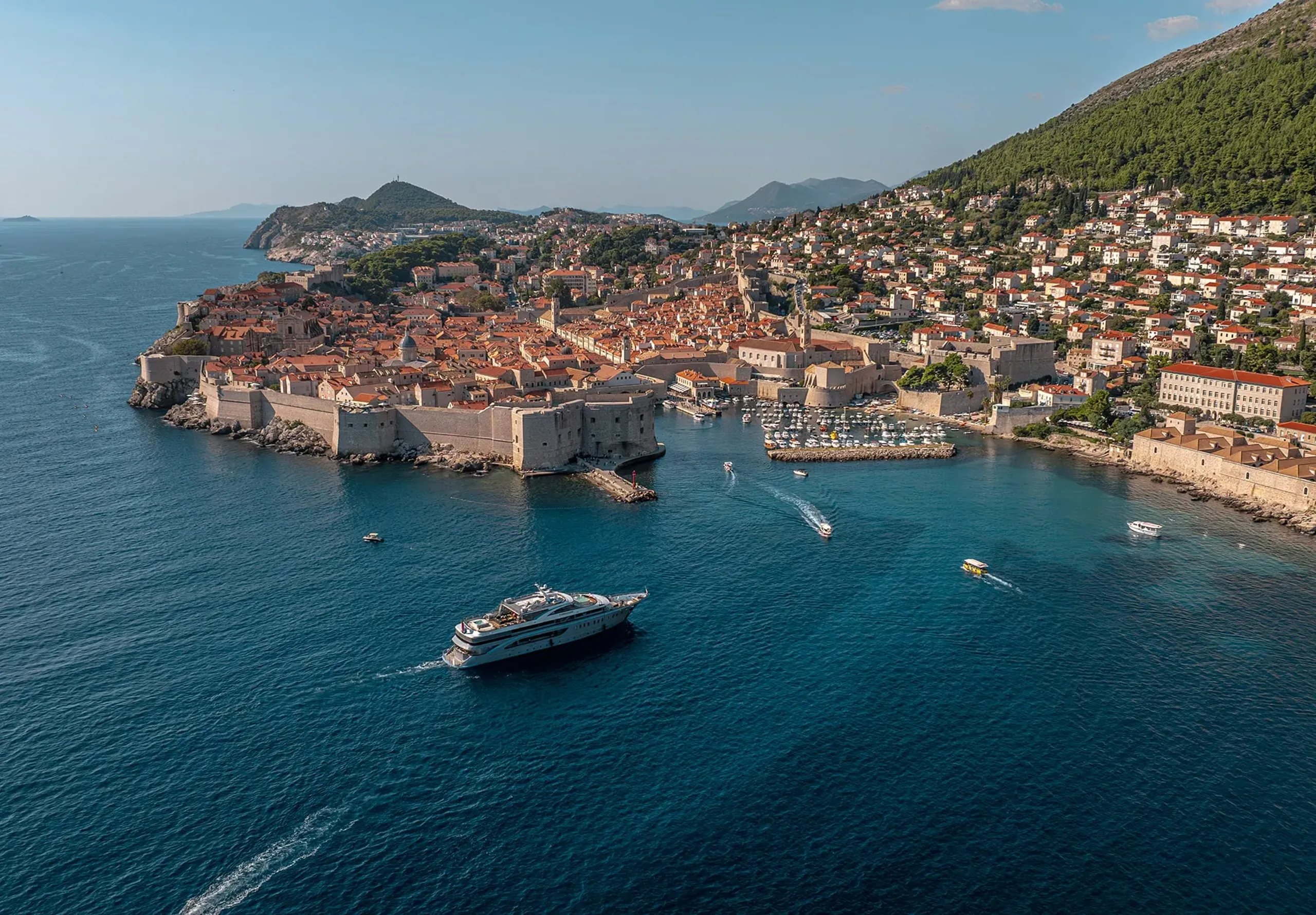 Luxury yacht cruising past Dubrovnik Old Town on the Croatian coast