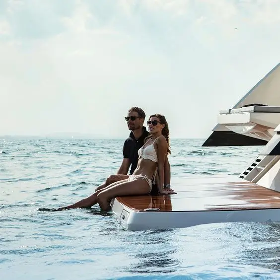 Couple sitting on the swim platform of a yacht at sea.