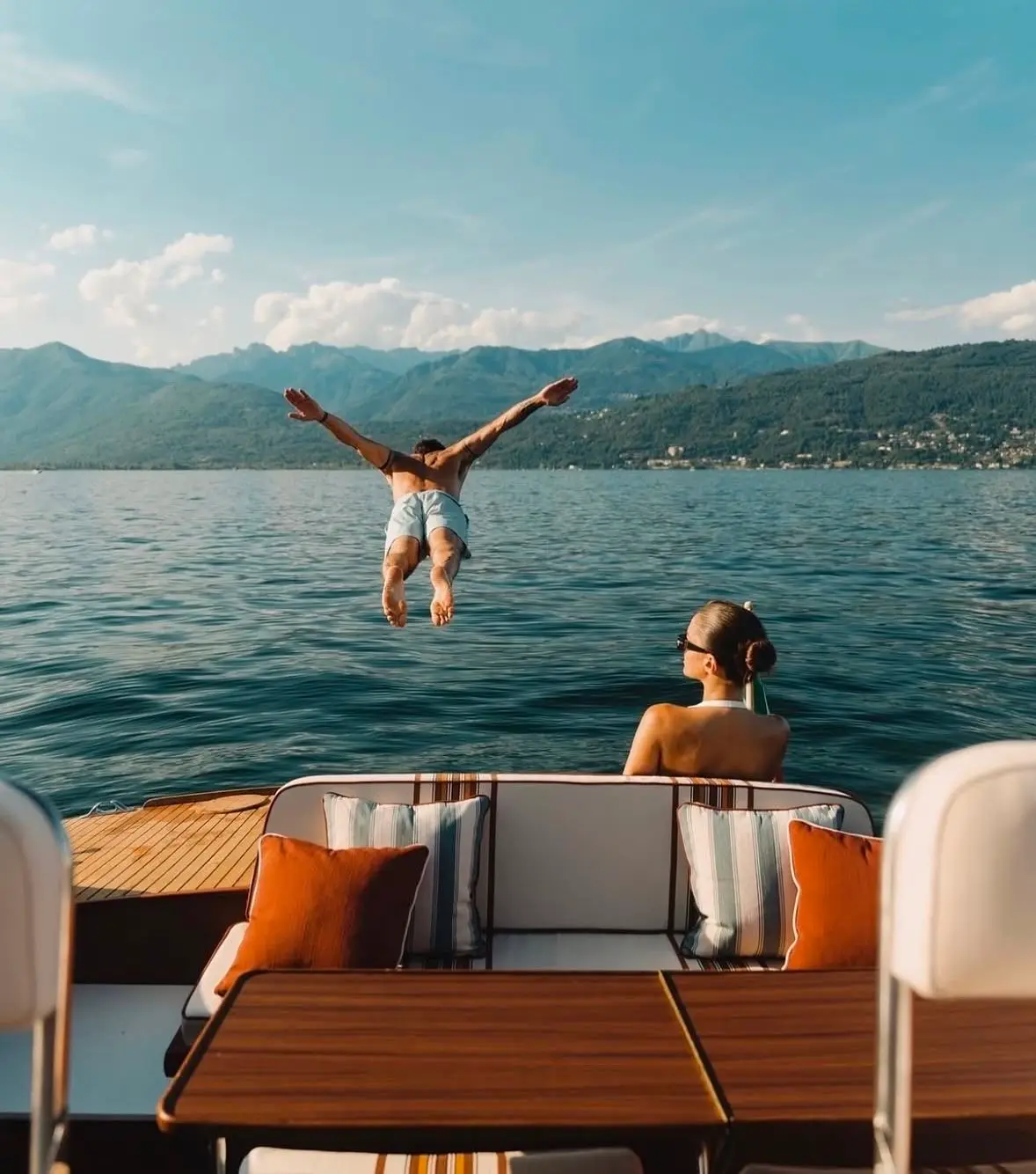 A guest diving from the deck of a yacht into calm water as another looks on